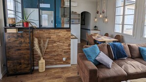 Un soggiorno moderno con un divano marrone, un tavolino in legno e un'area pranzo con tovaglia blu.