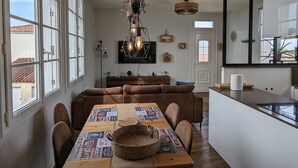 Zona pranzo con tavolo in legno, sedie imbottite marroni e lampadario a sospensione.