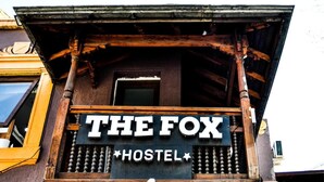 Uma varanda de madeira com uma placa que diz 'THE FOX HOSTEL'.