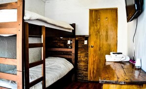 A bunk bed room with a wooden door and a small table with a towel and a cup. - The Fox Hostel (Santiago)