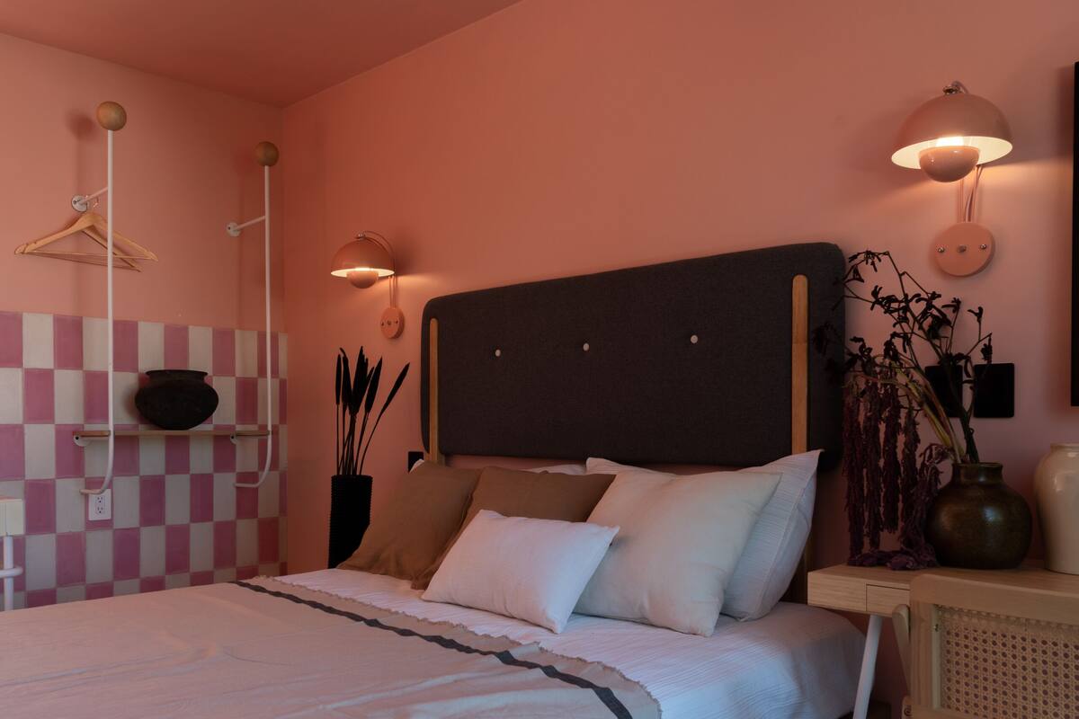Une chambre à coucher avec un lit, une table de chevet, une lampe et un mur à motifs à carreaux.