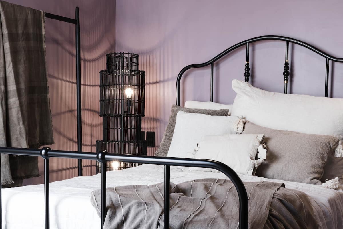 Une chambre à coucher avec un lit, une table de chevet, une lampe et une fenêtre.