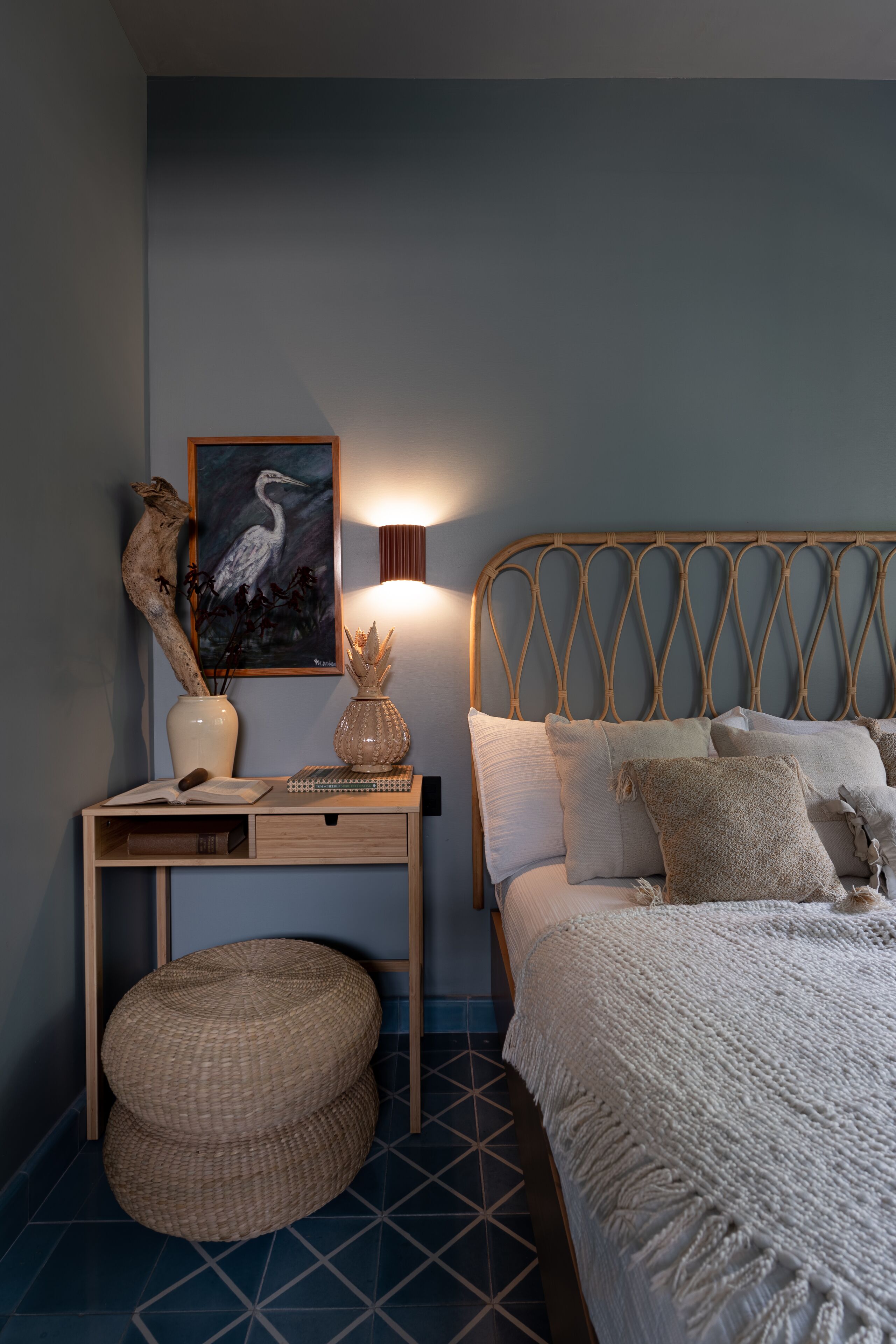 A bedroom with a bed, bedside table, and a wall-mounted lamp.