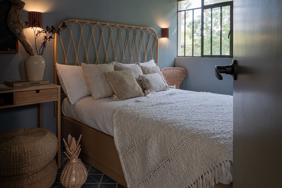 Une chambre à coucher avec un lit, des tables de chevet, une fenêtre et une porte.
