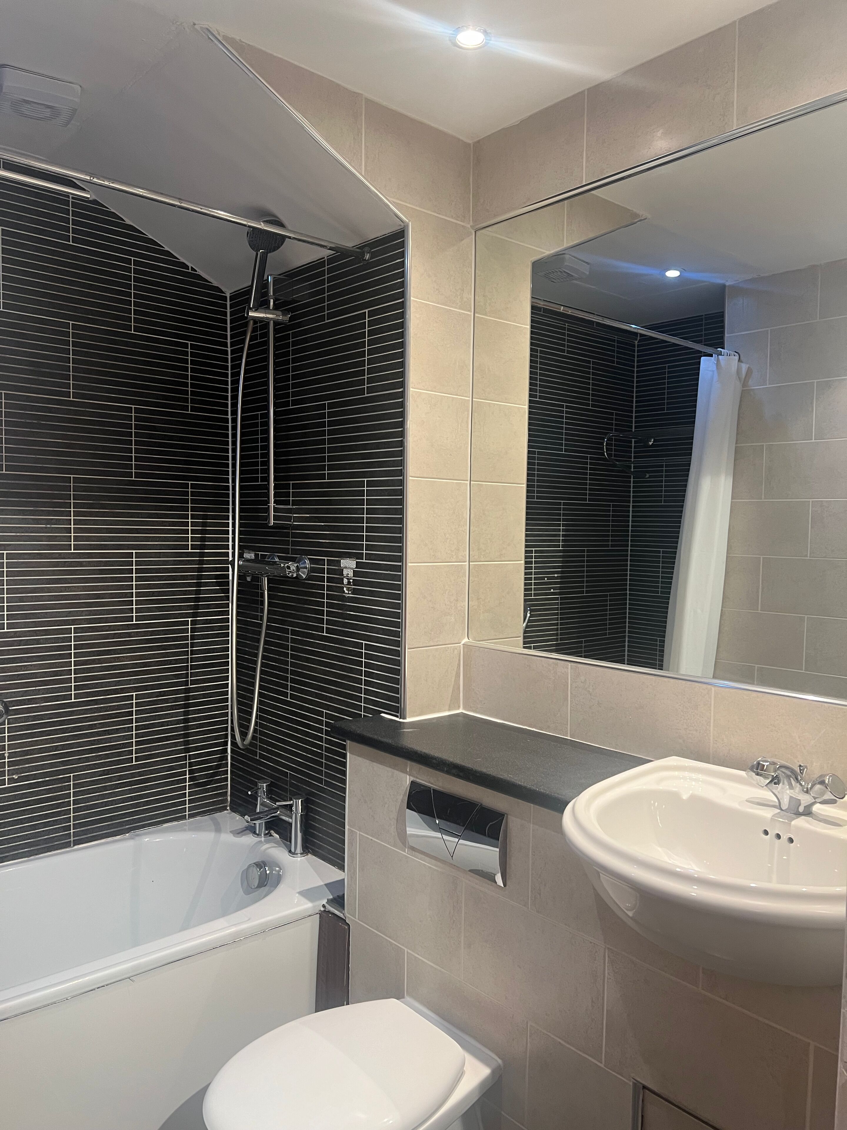 Et moderne badeværelse med badekar, toilet og håndvask.