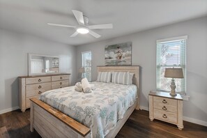 A bedroom with a bed, a nightstand, a ceiling fan, a window with blinds, and a painting on the wall. - Roomy 1 BDRM block from the BEACH Large Pool w/ a Private Courtyard (Port Aransas)