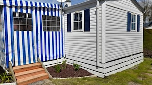 Una casa petita d'un pis, amb una tenda blava i blanca a ratlles i una antena parabòlica.