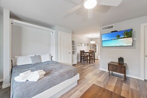 A bedroom with a bed, a TV, and a desk with chairs. - Cozy Studio Large Pool w/ a Private Courtyard and a Block from the Beach (Port Aransas)