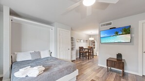 A bedroom with a bed, a TV, and a desk with chairs. - Cozy Studio Large Pool w/ a Private Courtyard and a Block from the Beach (Port Aransas)
