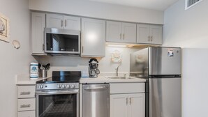 A modern kitchen with stainless steel appliances, including a stove, dishwasher, microwave, and refrigerator. - Cozy Studio Large Pool w/ a Private Courtyard and a 5 Min Walk to the Beach (Port Aransas)