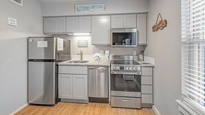 Una cocina moderna con electrodomésticos de acero inoxidable, armarios grises y un microondas integrado.