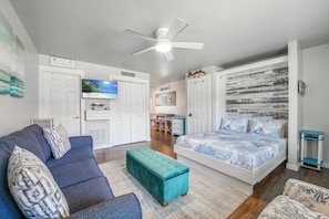 A bedroom with a bed, a sofa, a TV, and a ceiling fan. - Cozy Studio Large Pool w/ a Private Courtyard and a 5 Min Walk to the Beach (Port Aransas)
