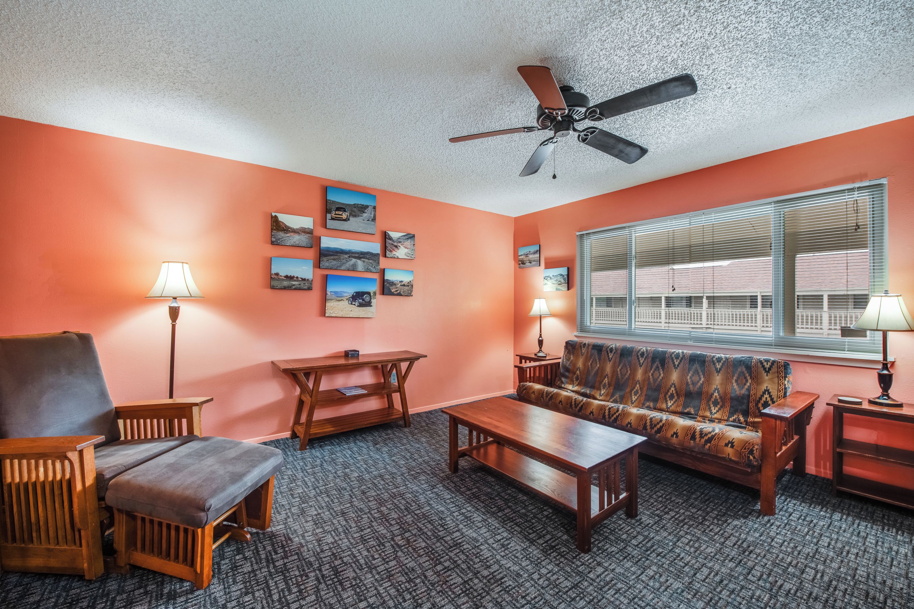 A living room with a sofa, armchairs, a coffee table, and a ceiling fan.