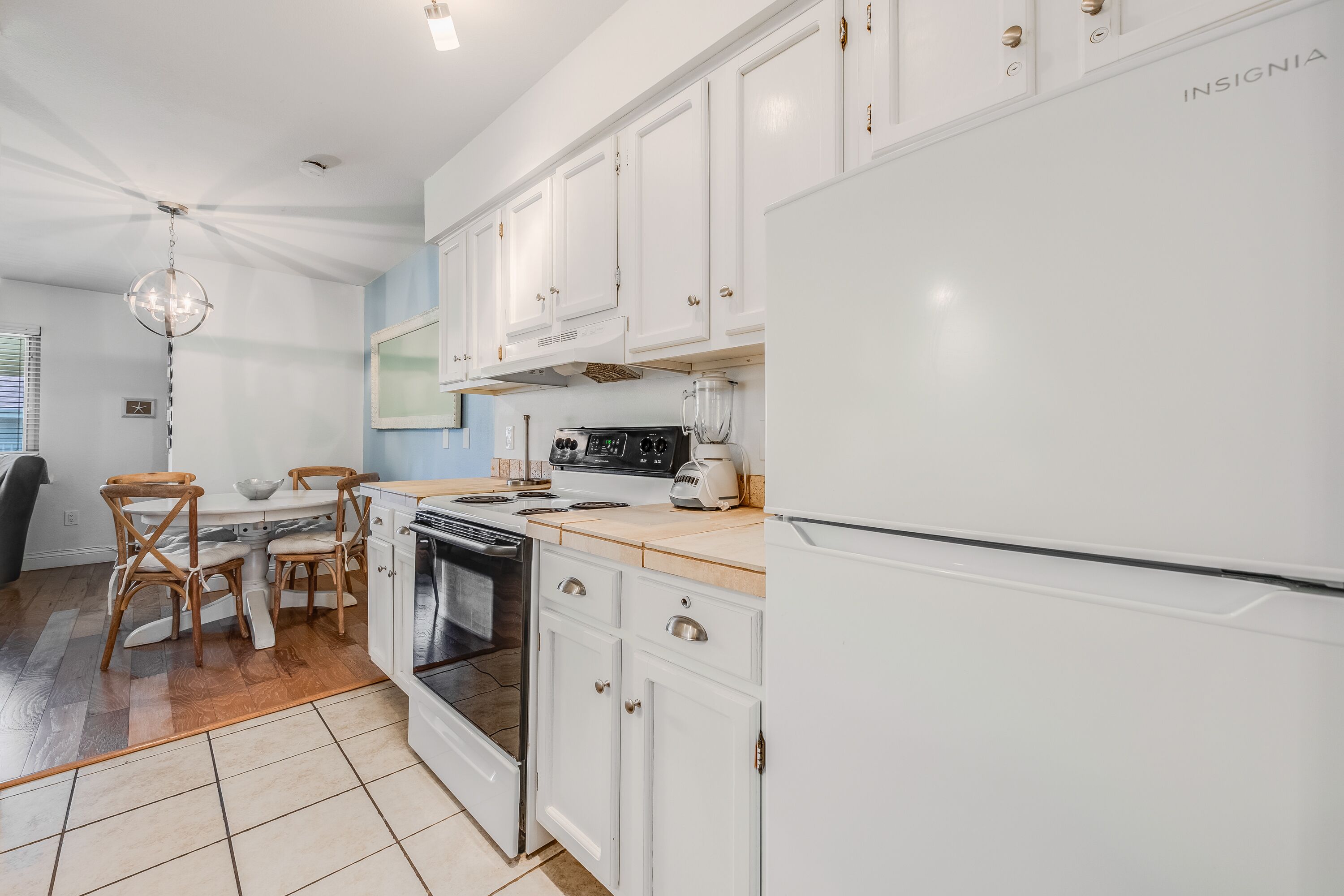 A modern kitchen with white cabinetry, a built-in oven, and a refrigerator.