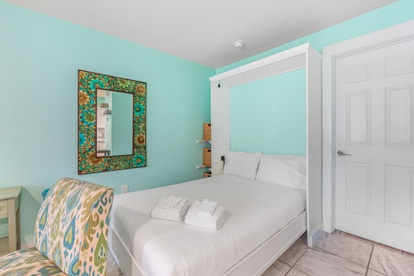 Un dormitorio con cama, sofá, espejo y armario.
