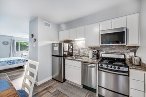 A modern kitchen with stainless steel appliances, white cabinetry, and a microwave above the stove. - Cozy Studio Large Pool w/ a Private Courtyard and a 5 Min Walk to the Beach (Port Aransas)