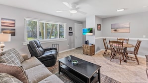 A living room with a sofa, coffee table, and TV. There's a dining area with a table and chairs. - Roomy 1 BDRM Large Pool w/ a Private Courtyard and a 5 Min Walk to the Beach (Port Aransas)