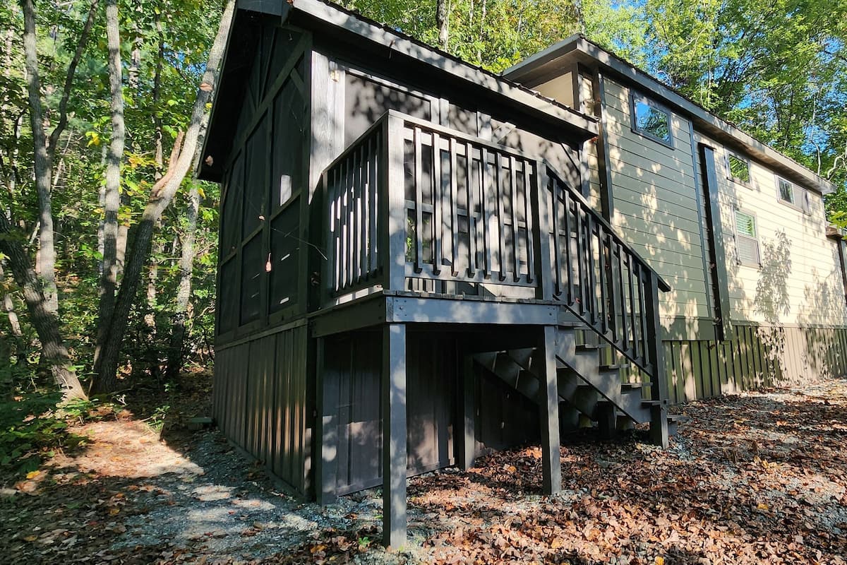 A rustic cabin with a wooden exterior, a balcony, and a staircase leading to the entrance.