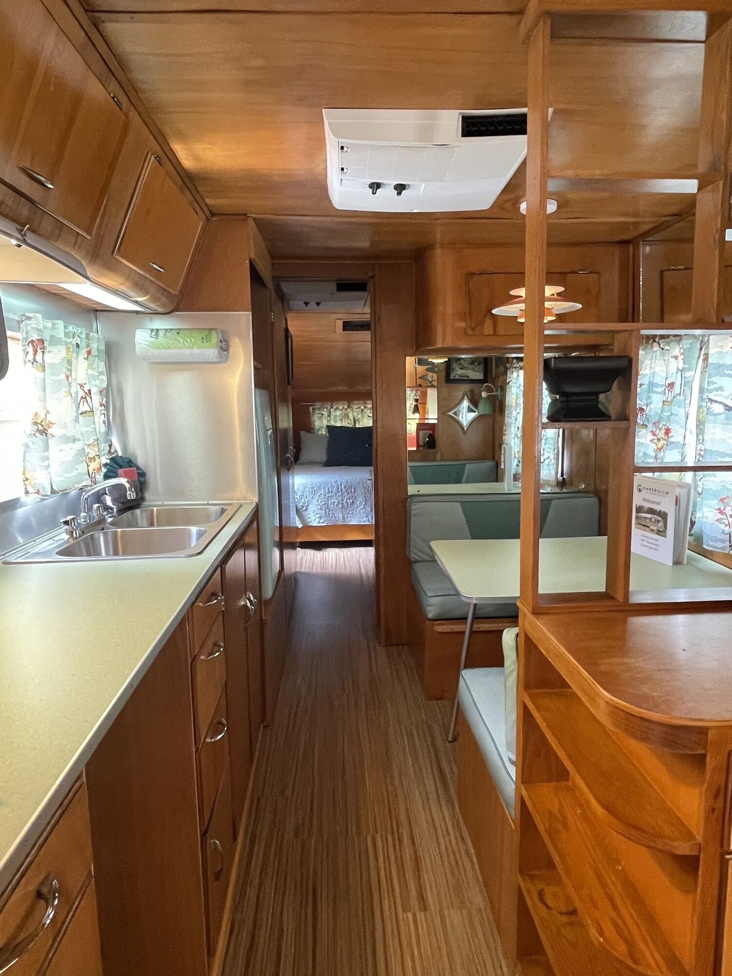 Interior compacto de una caravana con cocina americana, zona de comedor y una litera.