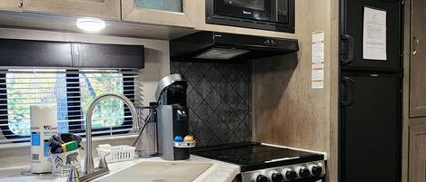 Une cuisine de taille réduite, dotée de meubles en bois, d’un four à micro-ondes, d’une cuisinière et d’un réfrigérateur.