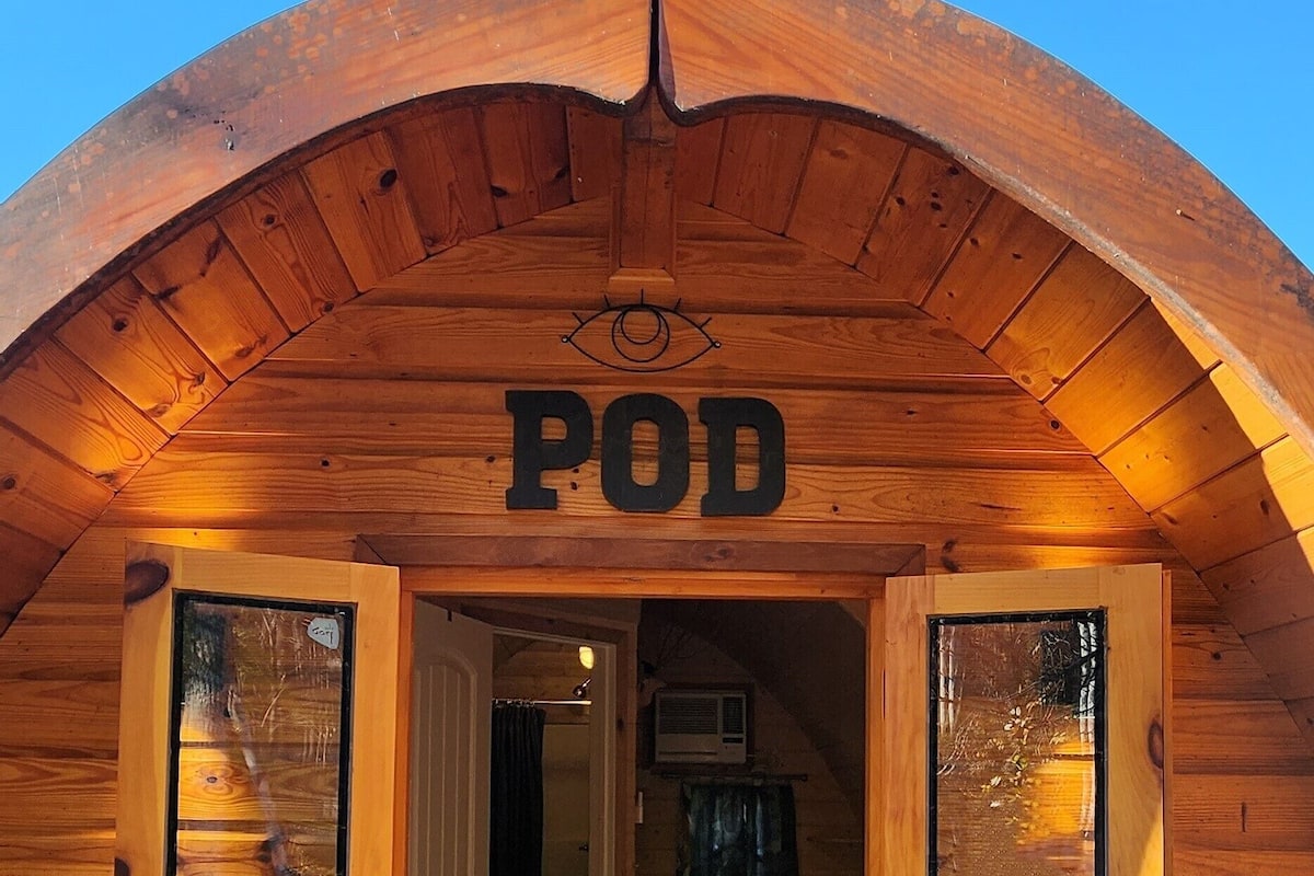 A wooden cabin entrance with a sign reading "POD".