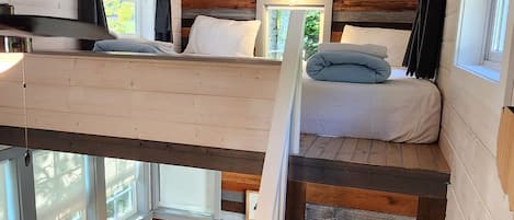 Una cabaña compacta con cama en altillo, sofá y escalera.