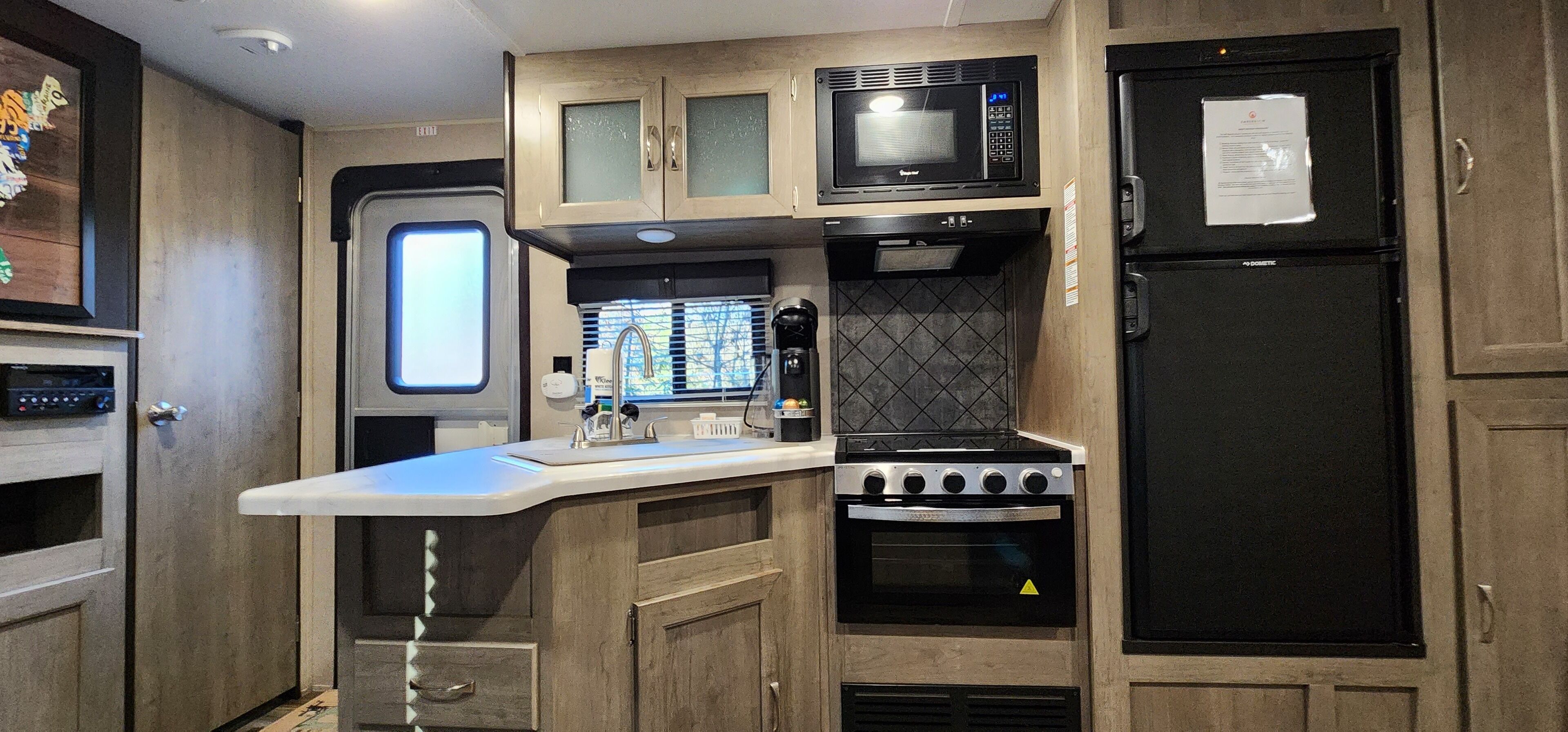 A compact kitchen with a microwave, oven, and refrigerator.