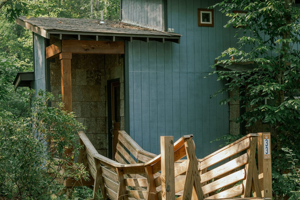 A rustic wooden cabin with a porch and a wooden bench.