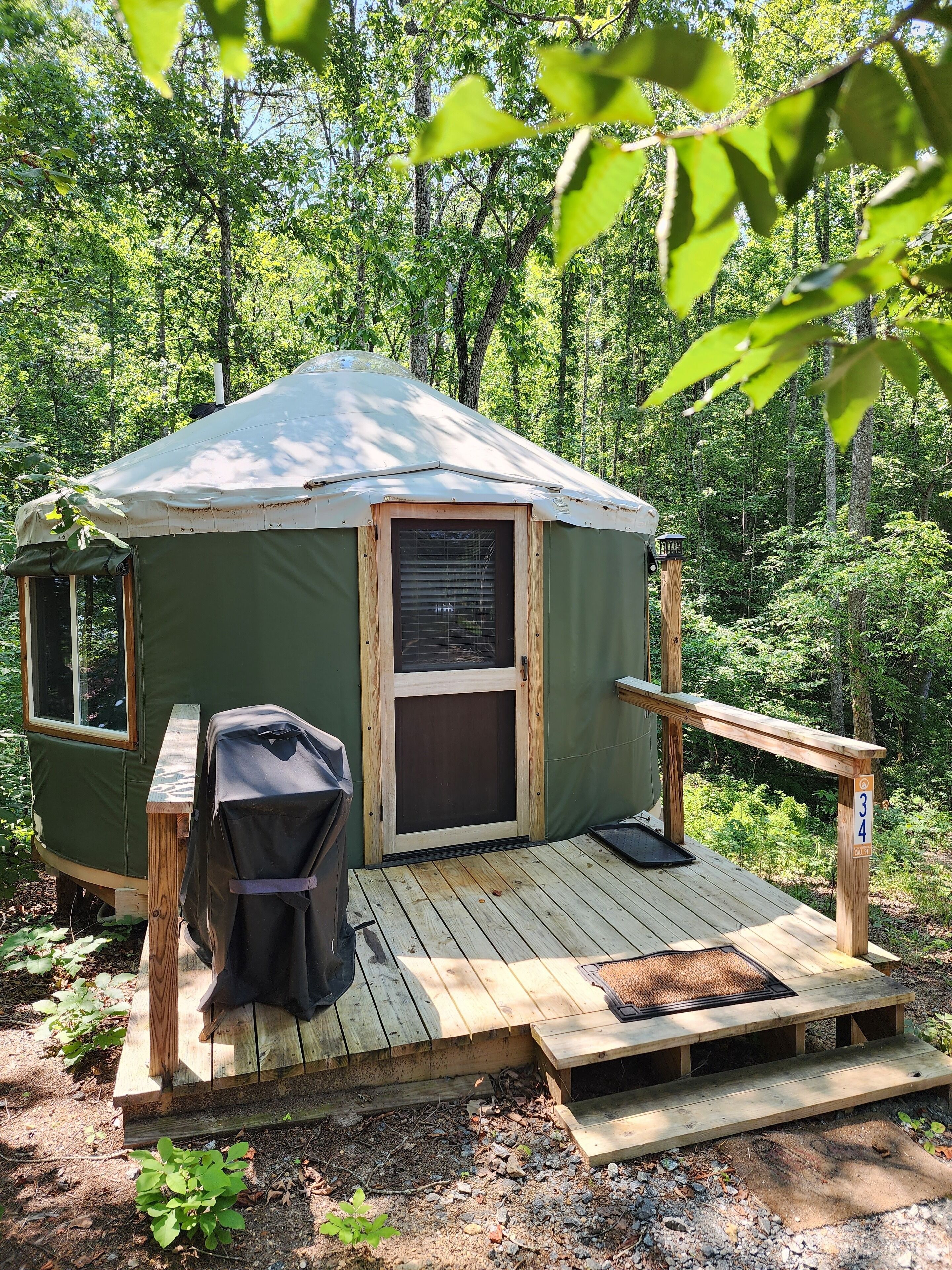 A green tent with a wooden deck, a grill, and a number 34 sign.