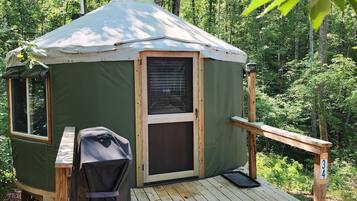 A green tent with a wooden deck, a grill, and a number 34 sign.