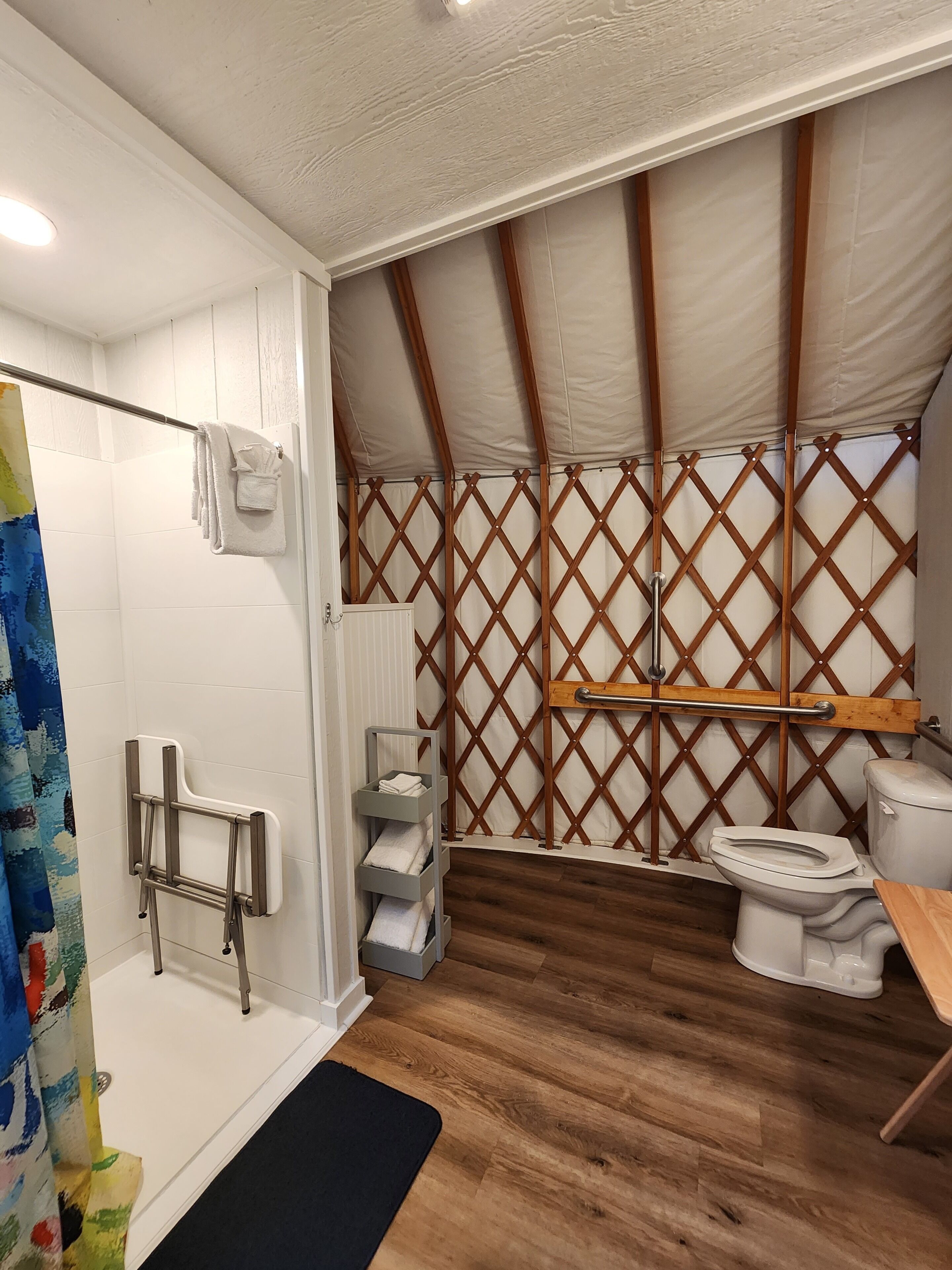 Une salle de bain avec douche, toilettes et plancher en bois.
