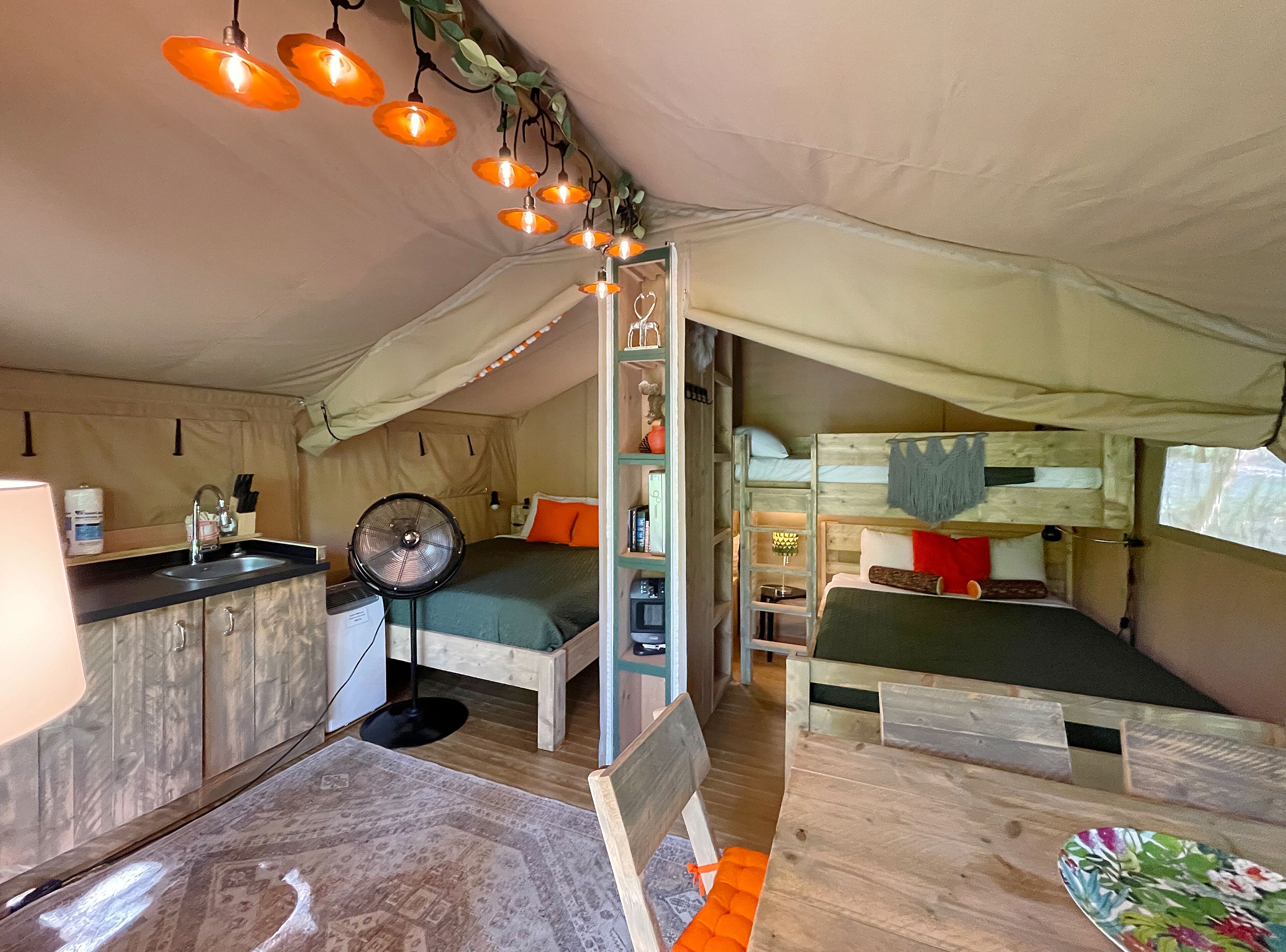Une tente compacte et bien éclairée, équipée d’un coin cuisine, d’un lit simple et d’un deuxième lit superposé.