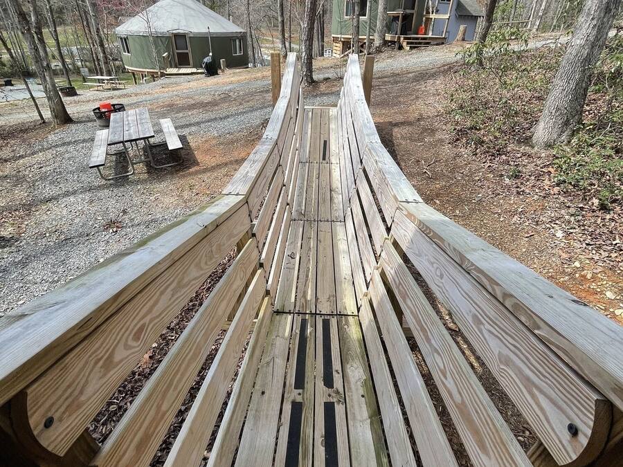 A wooden bench in a campground with picnic tables and cabins in the background.
