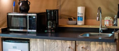 A compact kitchen with a microwave, coffee maker, and a sink.