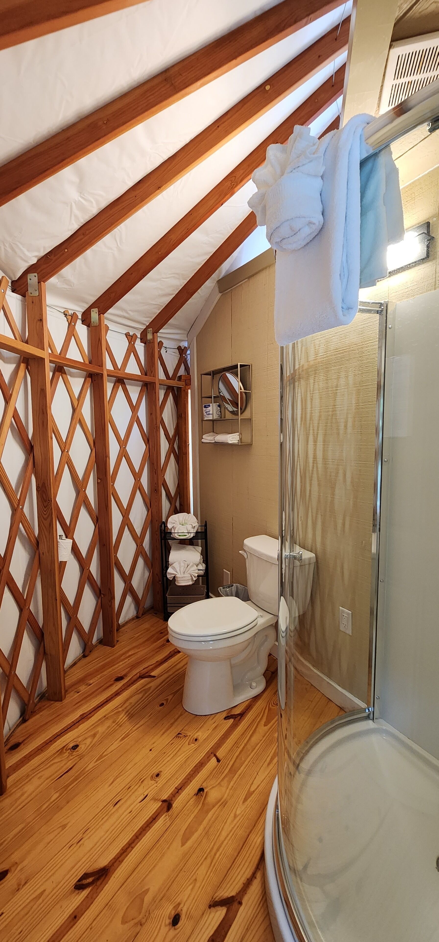 Une petite salle de bain avec un plafond en bois, des toilettes, un espace douche et un porte-serviettes avec des serviettes.