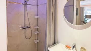 A modern bathroom with a shower, a sink, and a mirror.