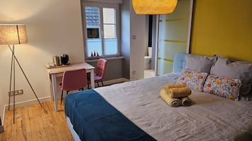 Un dormitorio con cama, escritorio, silla, lámpara y ventana.