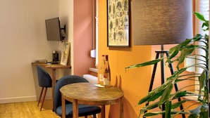 A cozy room with a wooden table, two chairs, a framed botanical print, a lamp, and a plant.