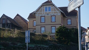 Un edificio grande de dos pisos con estilo arquitectónico tradicional, que destaca por un tejado a dos aguas y numerosas ventanas.