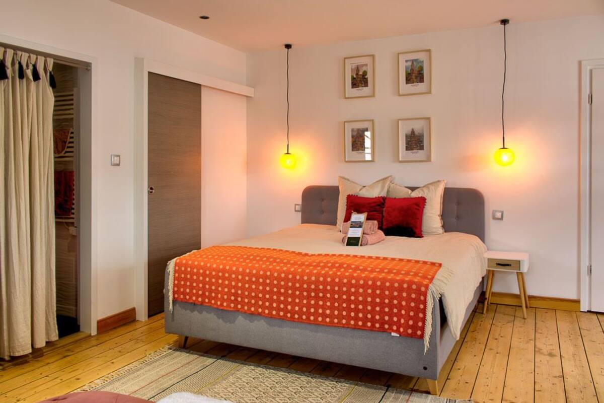 Un dormitorio con cama, mesita de noche, armario y puerta.
