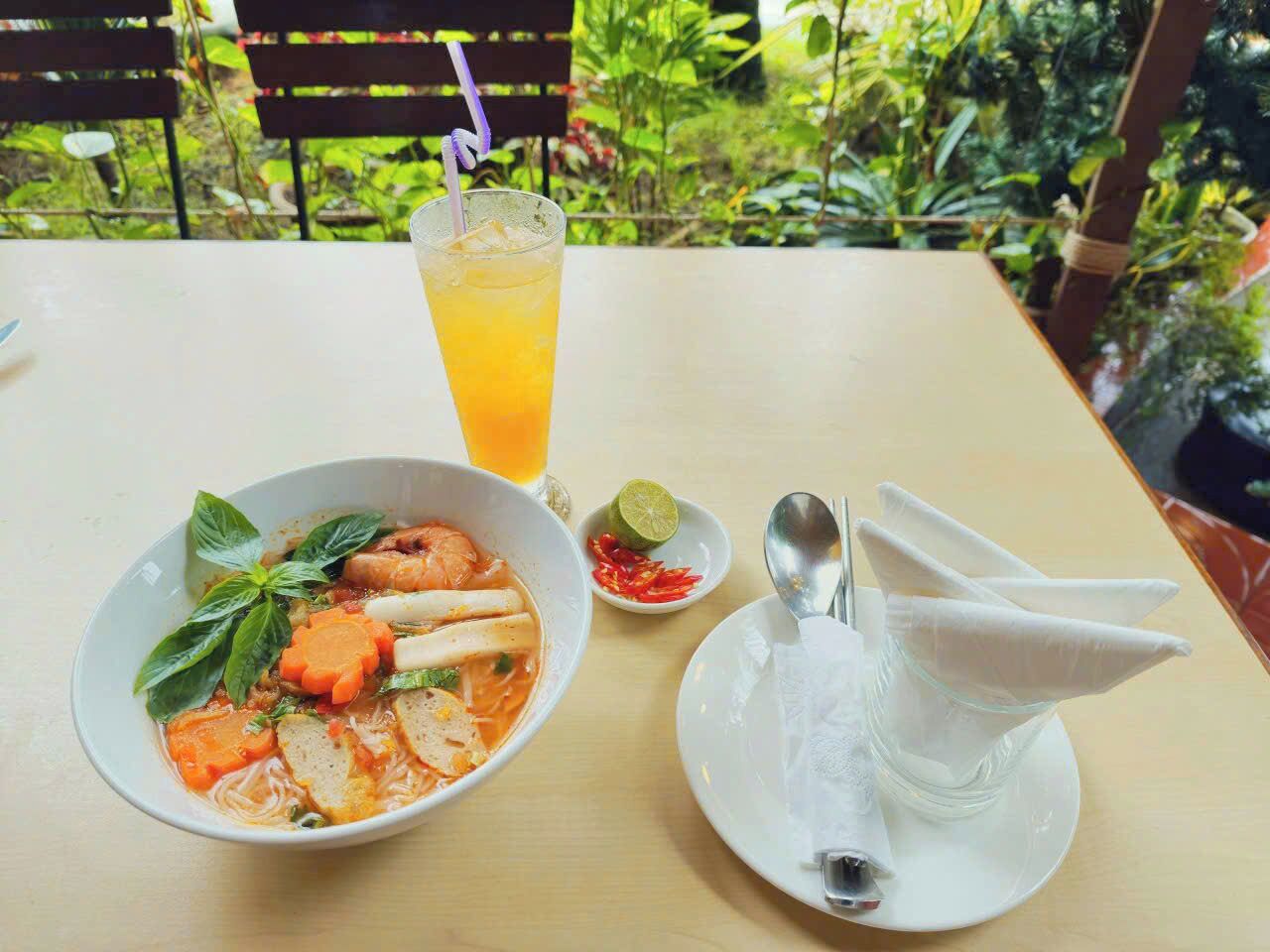 Une table avec un bol de soupe, un verre de jus d’orange, une tranche de citron vert et une cuillère.