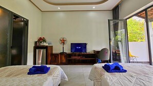 Habitación de hotel con dos camas, televisor, escritorio y ventana grande.