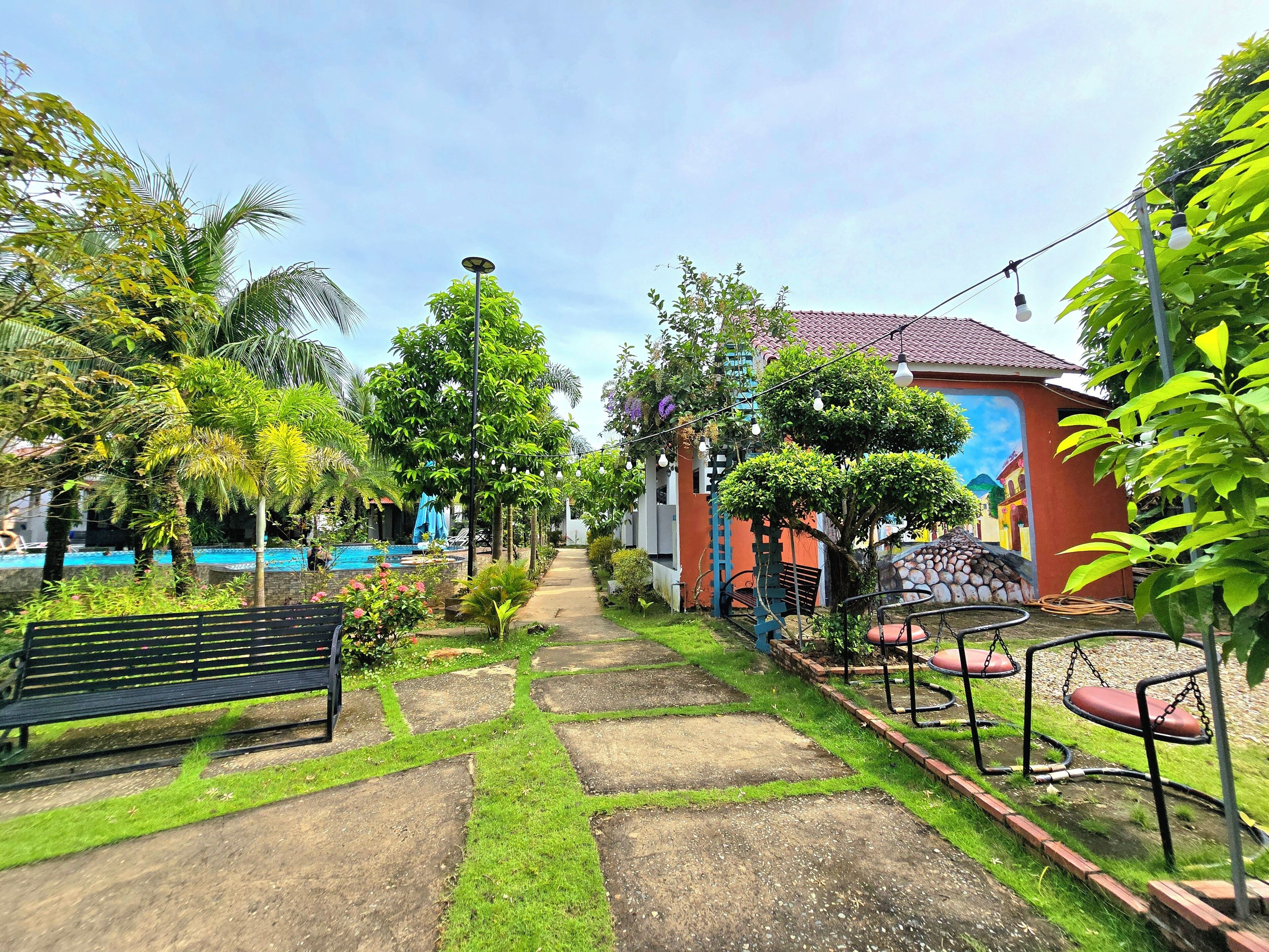 A garden pathway leading to a pool area with benches and a swing set.