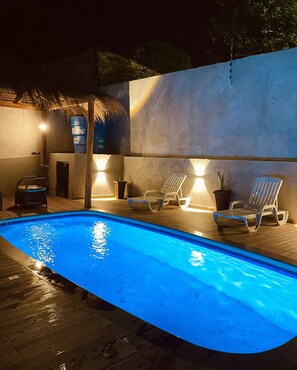 A swimming pool with lounge chairs and a thatched roof structure. - Mansión Blanca Resort Del Este,
The heart of Ciudad Del Este, Paraguay (Ciudad del este)