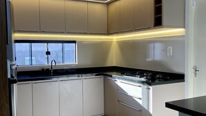 Una cocina moderna con armarios blancos, encimeras negras e iluminación debajo de los armarios.