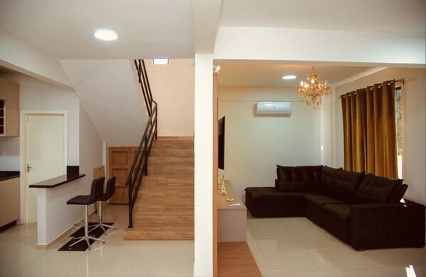 A modern living space with a staircase, a black sectional sofa, and a dining area with chairs. - Mansión Blanca Resort Del Este,
The heart of Ciudad Del Este, Paraguay (Ciudad del este)