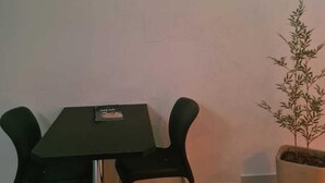 A dining area with a table and chairs, a potted plant, and a television mounted on the wall. - PRIME MOTEL AMERICANA (Americana)