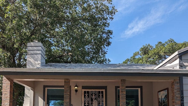 A single-story house with a brick exterior, a front porch with two wicker chairs, a metal gate, and a small step leading to the entrance. - House in Miami (Miami)