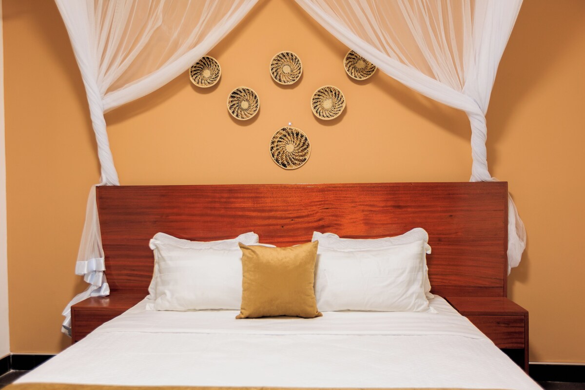A bed with white and gold bedding, a wooden headboard, and a decorative wall with circular patterns.