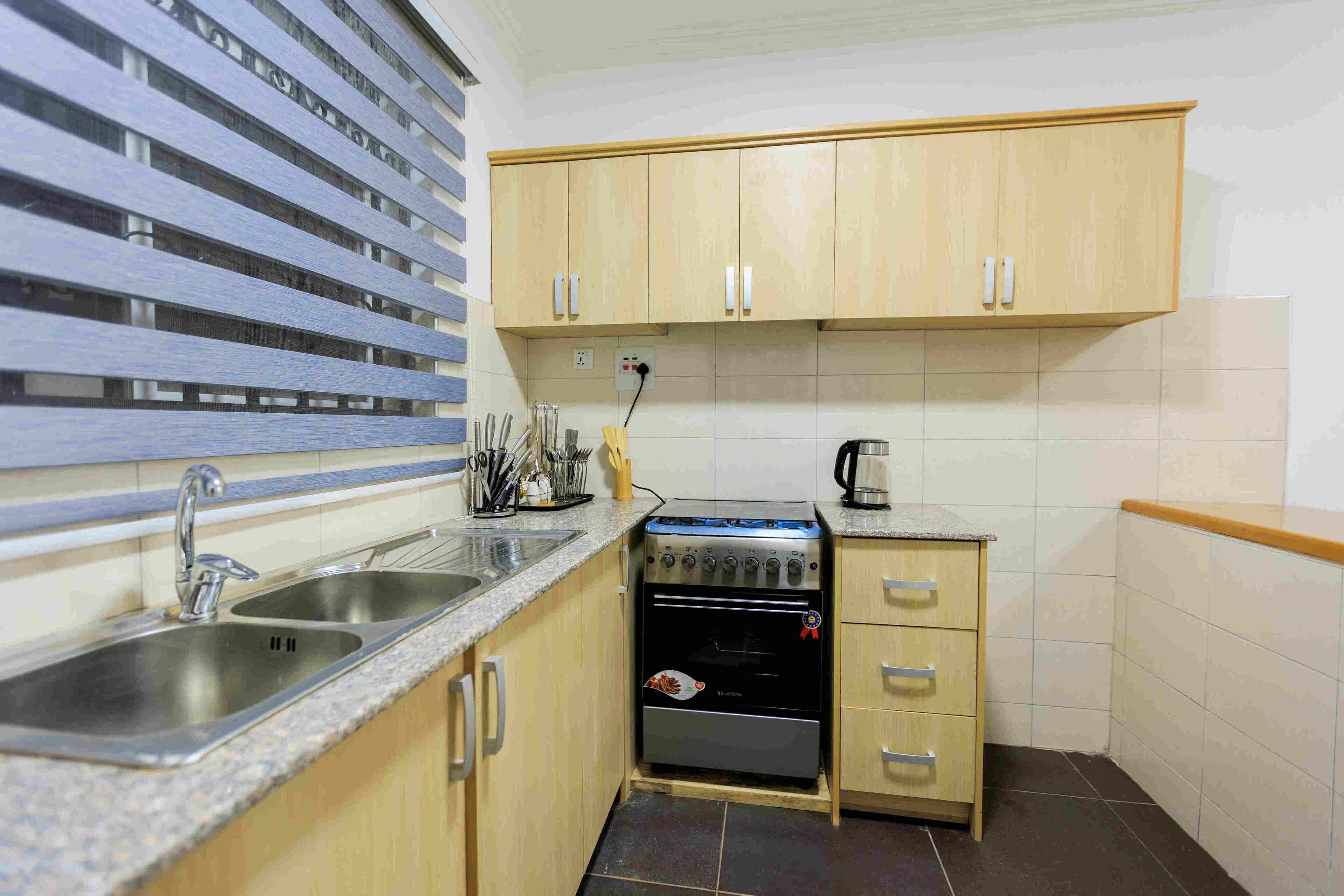 A compact kitchen with a sink, stove, and wooden cabinets.